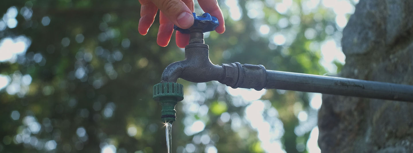 Hand turning on water spigot outside
