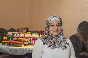 Woman standing in front of a table that has various bottles of products she sells