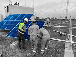 Four men in hard hats working on a commercial solar panel construction site
