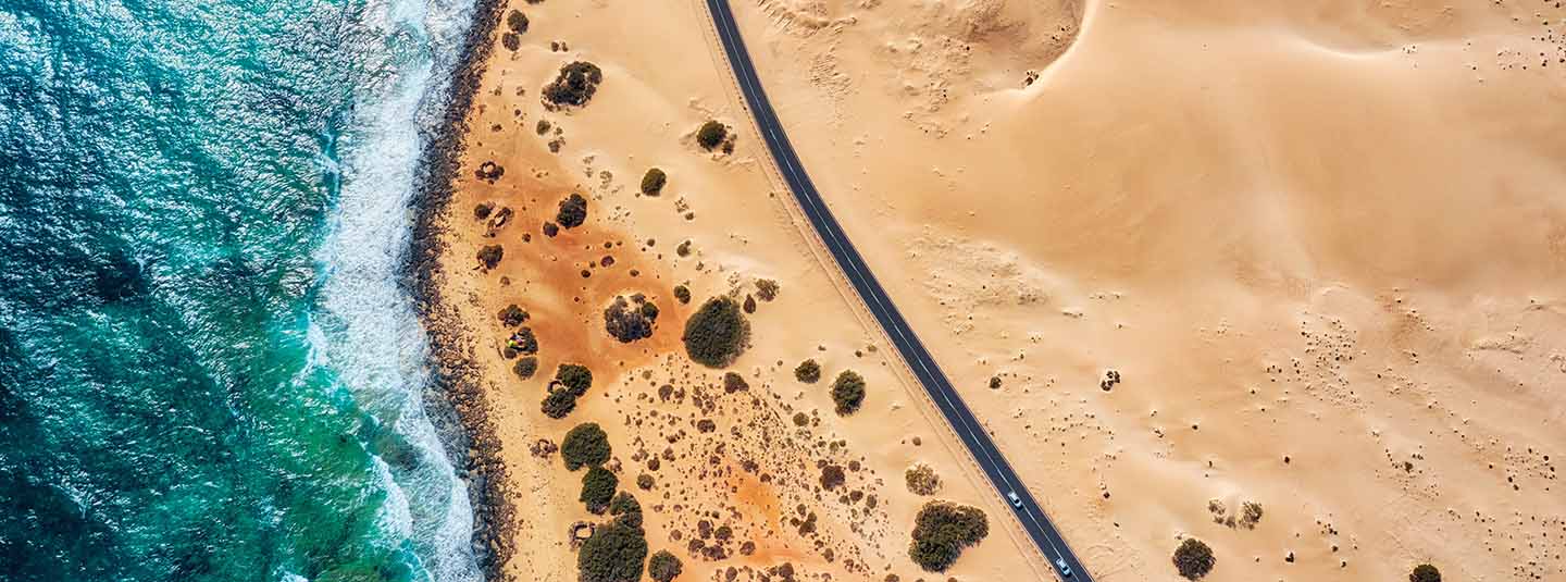 Aerial view of a road running parallel to a beach