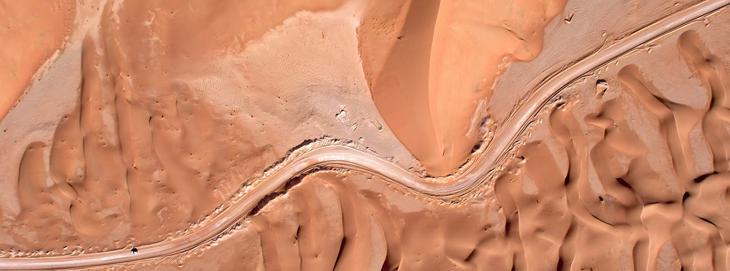 Aerial view of road through desert dunes