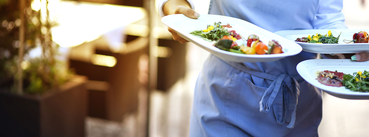 Waiter carrying three plates of food