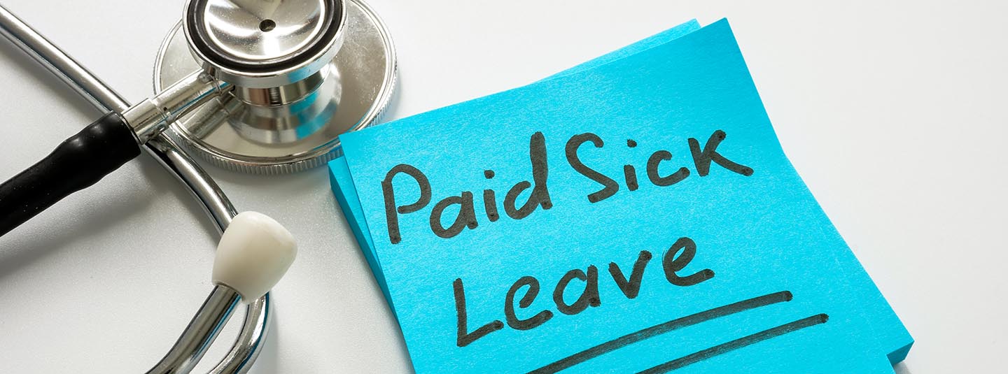 Paid sick leave written on post-it note beside a stethoscope