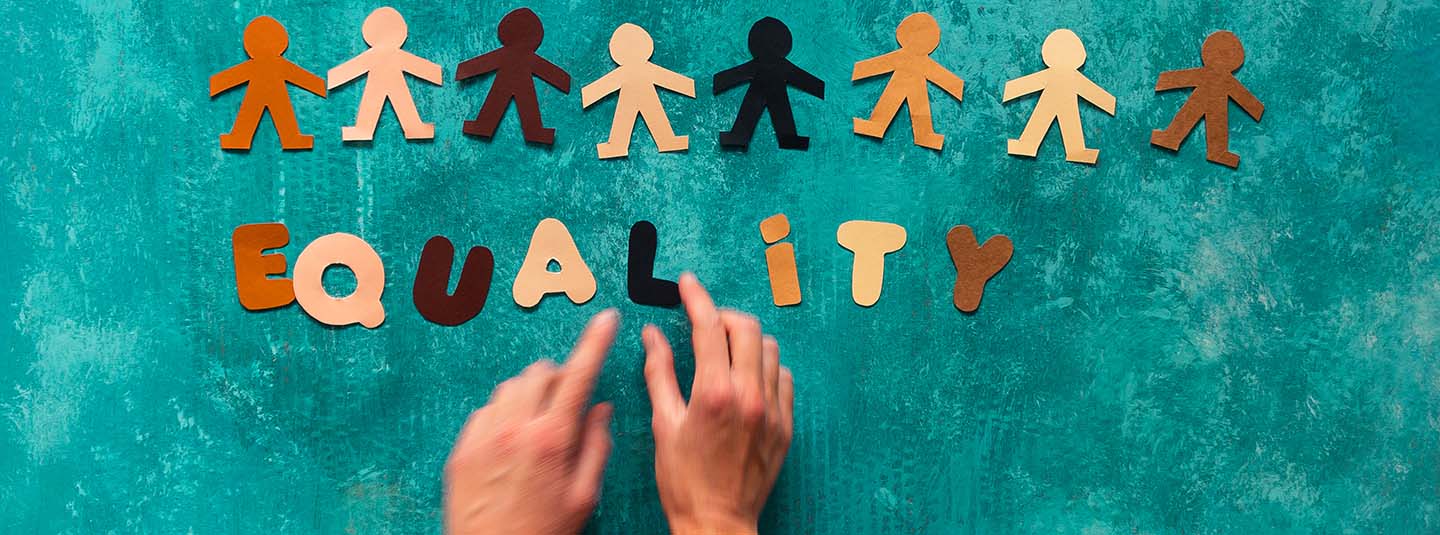 Paper cut-out people and letters spelling equality on a green background